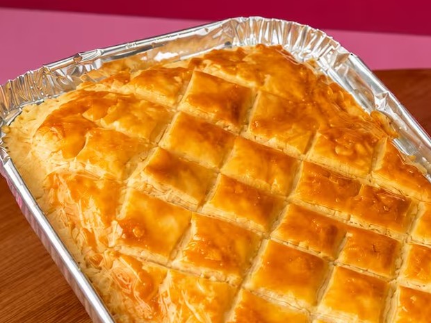 Empadão de frango dourado na marmita de alumínio, com a tampa riscada em losango